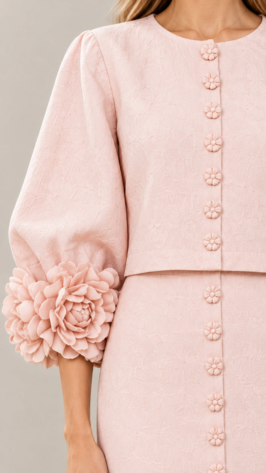 Close-up detail of textured fabric, decorative buttons, and 3D floral appliqués on sleeve cuffs