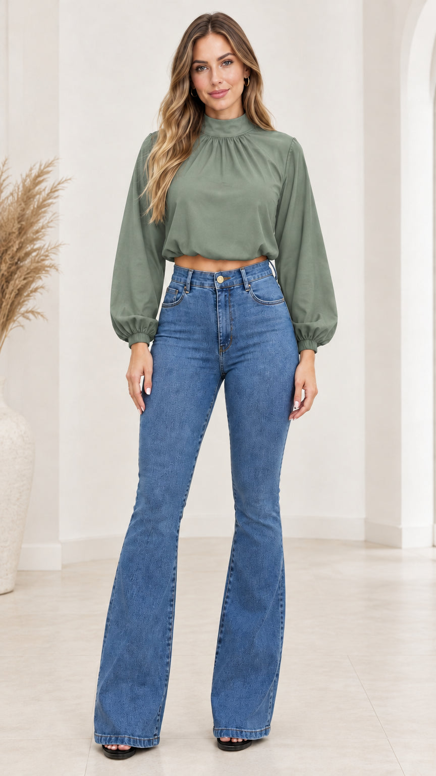 Front view of model wearing sage green lantern-sleeve crop top with blue flare jeans